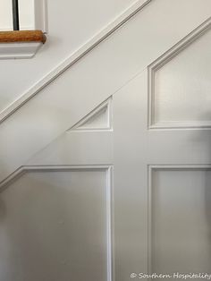 a cat sitting on top of a wooden floor next to a white stair casement