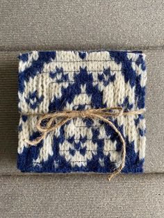 a piece of blue and white knitted material tied up to a gray surface with rope