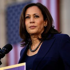 a close up of a person at a podium with an american flag in the background