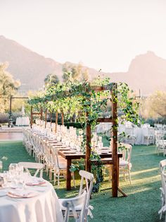 an outdoor wedding setup with white linens and greenery