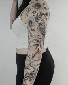 a woman's arm with flowers and birds tattooed on the back of her arm