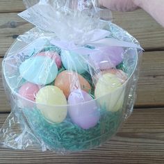 a plastic bag filled with eggs on top of a wooden table next to a person's hand