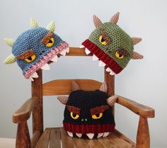 two crocheted monster hats sitting on top of a wooden chair