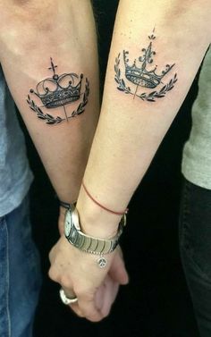 two people are holding hands with tattoos on their arms, one has a crown and the other has an arrow