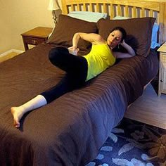 a woman laying on top of a bed next to a night stand and nightstands