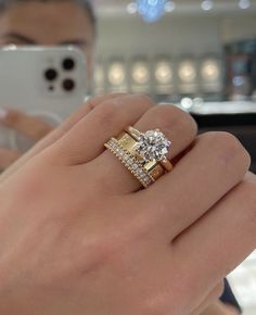 a person holding a cell phone in their hand with a diamond ring on the finger