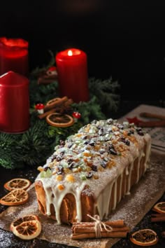 a cake with white icing and orange slices on a wooden board next to candles