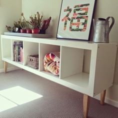 a white shelf with some books and plants on it