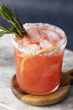 a drink in a glass with a rosemary garnish on top