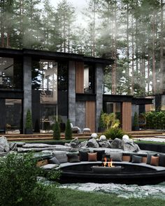 an outdoor fire pit surrounded by rocks and grass in front of a modern house with large windows