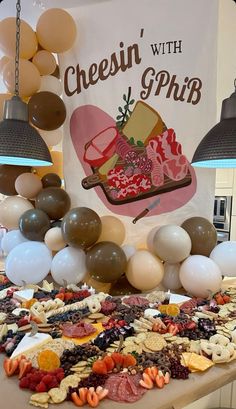 a table topped with lots of different types of food and balloons hanging from the ceiling