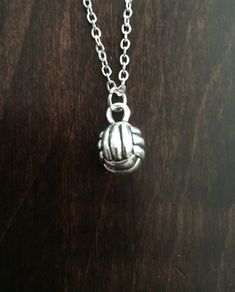 a silver necklace with a ball on it sitting on top of a wooden table next to a chain