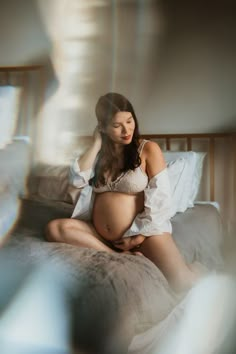 a pregnant woman sitting on top of a bed