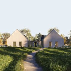 a white house sitting on top of a lush green field next to a dirt road