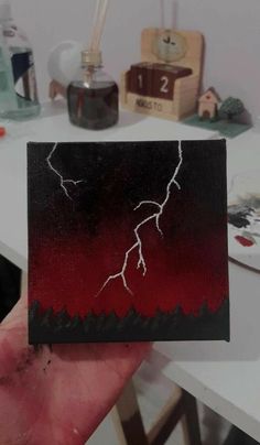 a hand holding up a piece of art with a lightning design on it's side