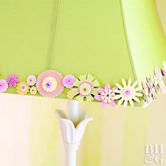 a lamp that has flowers on it next to a green lampshade with pink and yellow trim