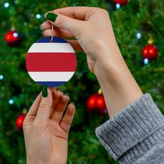 a person holding a rainbow ornament in front of a christmas tree