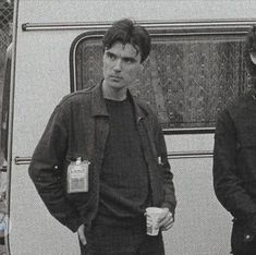 two men standing next to each other in front of a van