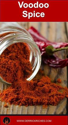 a glass jar filled with red spice next to peppers on top of a wooden table