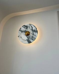 a white and black clock mounted to the side of a wall