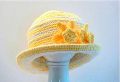 a crocheted hat with flowers on it sitting on top of a white table