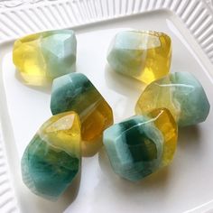 some yellow and green rocks on a white plate with water droplets in it's center