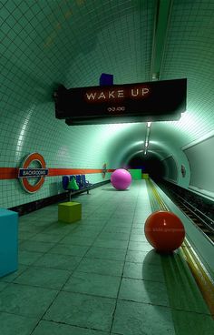 an underground subway station with colorful balls in the foreground and a sign that says wake up