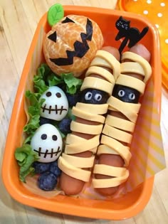 an orange tray filled with halloween food on top of a wooden table