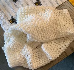 two white crocheted baby blankets sitting on top of a wooden floor next to a yellow rug