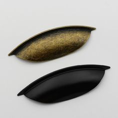 two black and gold leaf shaped objects on a white surface