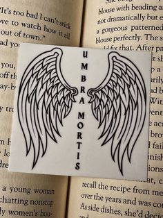 an open book with black and white wings on it