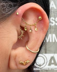 a woman wearing gold ear piercings with spikes and stars on the side of her ear