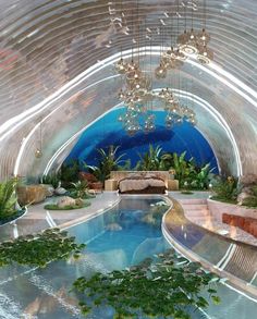 an indoor swimming pool with chandeliers hanging from the ceiling and plants growing in it