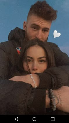 a man and woman hugging each other with the sky in the back ground behind them