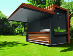 an outdoor shower with wooden slats on the side and plants growing in it, surrounded by green grass