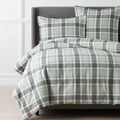 a bed with plaid sheets and pillows on it