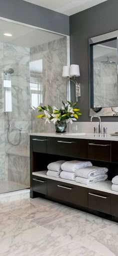 a bathroom with two sinks, mirrors and towels on the counter top in front of a shower