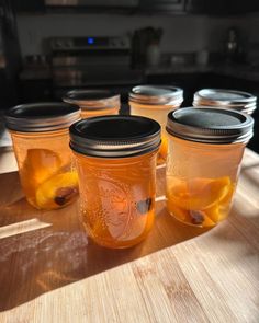 four jars filled with liquid sitting on top of a wooden table