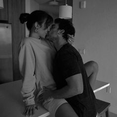 a man kissing a woman on the cheek in front of a kitchen counter with an island