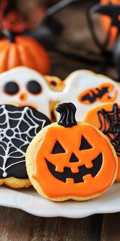 decorated halloween cookies on a white plate with pumpkins and ghost faces in the background