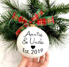 someone holding up a christmas ornament with the name and date on it