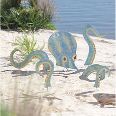 two blue octopus sculptures sitting on top of a sandy beach