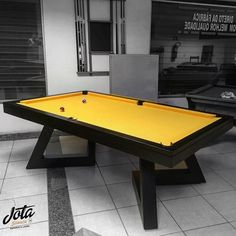 a yellow pool table in a room with black and white tiles