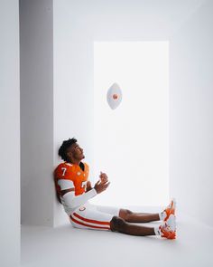 a man in an orange and white uniform sitting on the floor