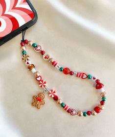 ♡ Jolly Gingerbread Christmas Phone Charm Strap ♡ Approximately 8 inches in length from top of cord to bottom of beads ♡Made with: * black waxed cord  * acrylic beads * plastic beads * clay beads ♡ Beads and bead colors may vary but will look very similar to the phone charm pictured ♡ Please contact me if you have any questions or any bead color preferences DISCLAIMER:  * All of our phone charms are not intended for small children  * Beads are a choking hazard for children * BestieBeadz assumes How To Phone Charm, Christmas Phone Charm Ideas, Christmas Charms Diy, Christmas Phone Charm, Small Bussines Idea, Clay Bead Phone Charm Ideas, Diy Christmas Jewelry Ideas, Christmas Beads Ideas, Christmas Phone Ideas