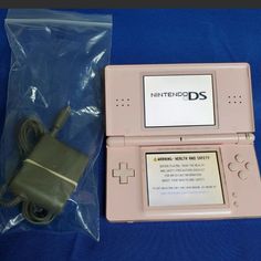 an old nintendo ds game system and its packaging on a blue cloth covered tablecloth