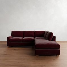 a red couch sitting on top of a hard wood floor next to a white wall