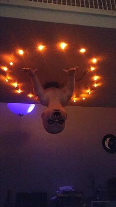 a man is upside down on the ceiling with his hands in the air and lights above him