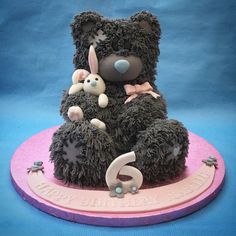 a birthday cake made to look like a teddy bear with two rabbits on its back