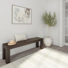 a white room with a wooden bench next to a potted plant and a painting on the wall